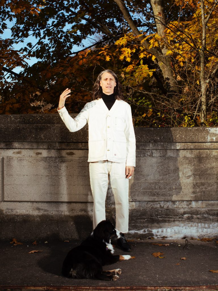 robert in white suit standing in front of trees